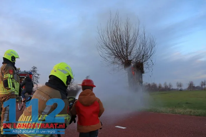 Jongentje in brandweerkleding helpt brandweer bij blussen brandende knotwilg Sprang-Capelle 112 De Langstraat