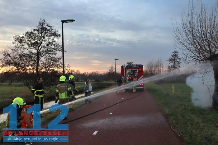 Jongentje in brandweerkleding helpt brandweer bij blussen brandende knotwilg Sprang-Capelle 112 De Langstraat